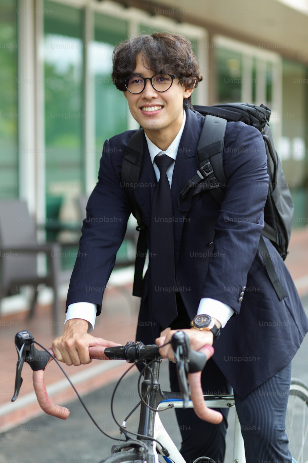 Portrait of handsome young businessman in formal suit looking forward while riding on his bicycle.
