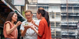 Group of Asian woman and LGBTQ people friends tourist enjoy eating traditional street food fried shrimp gyoza together at Chinatown night market in Bangkok, Thailand. Travel and street food concept