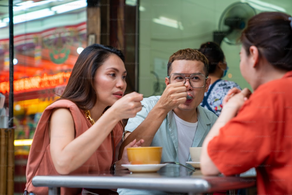 Group of Asian people friends tourist having dinner together at chinatown street night market in Bangkok city, Thailand. Male and female friend enjoy outdoor lifestyle nightlife and eating street food