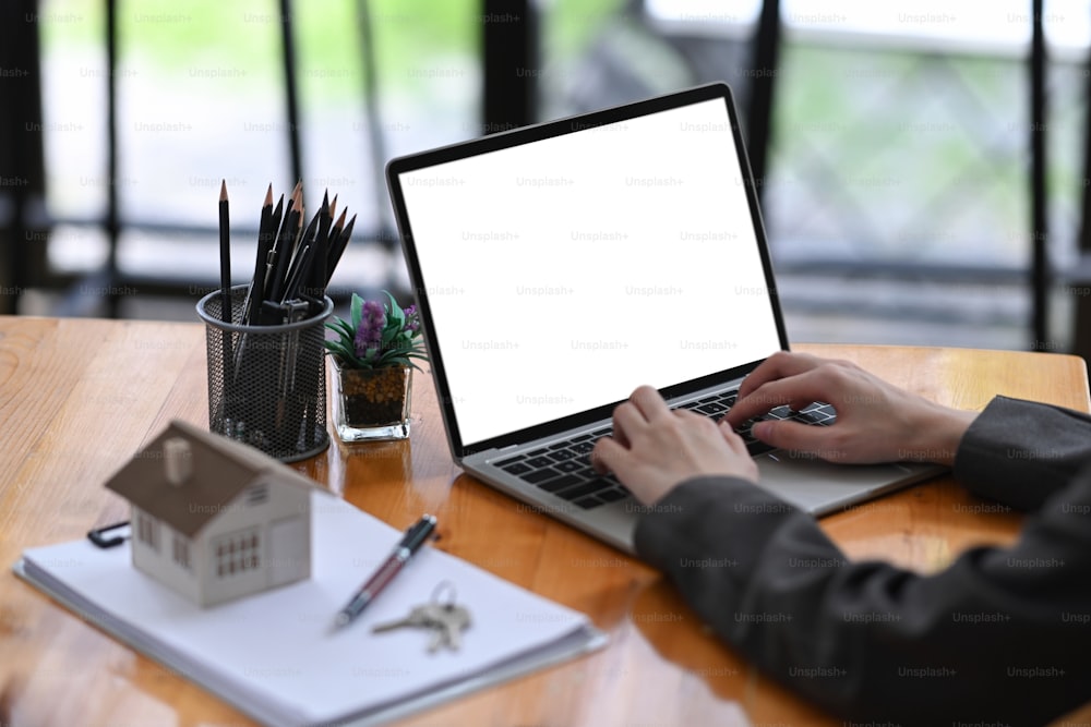 Real estate agent woman using laptop computer on wooden table.