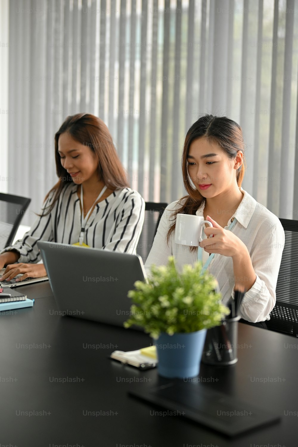 Company's officer working on laptop computer while drinking coffee at her working desk.