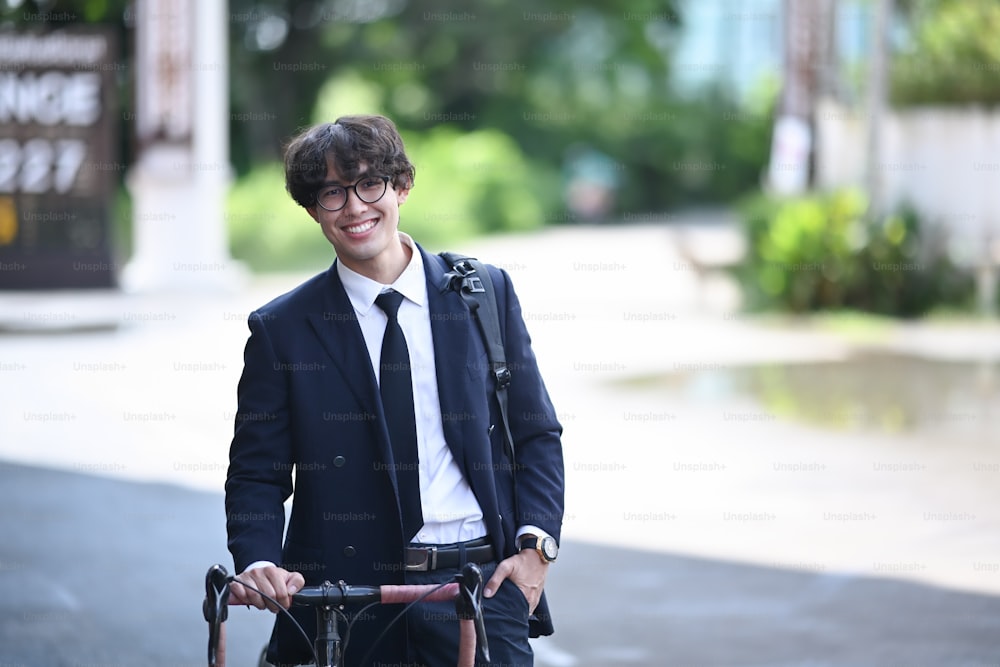 Uomo d'affari felice che cammina sulla strada della città con una bicicletta per il suo tragitto mattutino al lavoro.