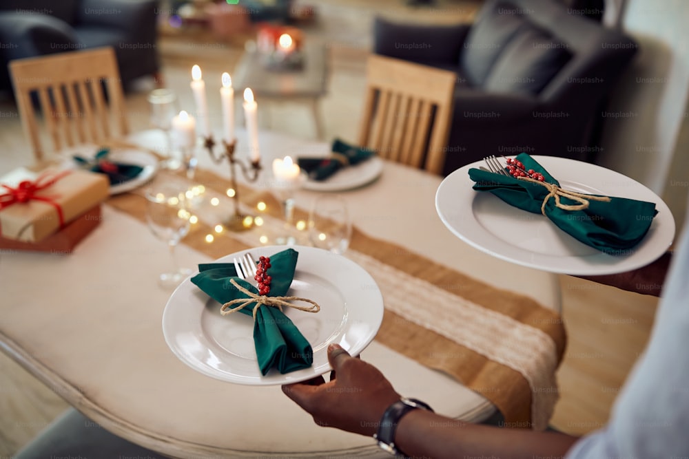 Close-up of black man setting dining table for Christmas party at home.