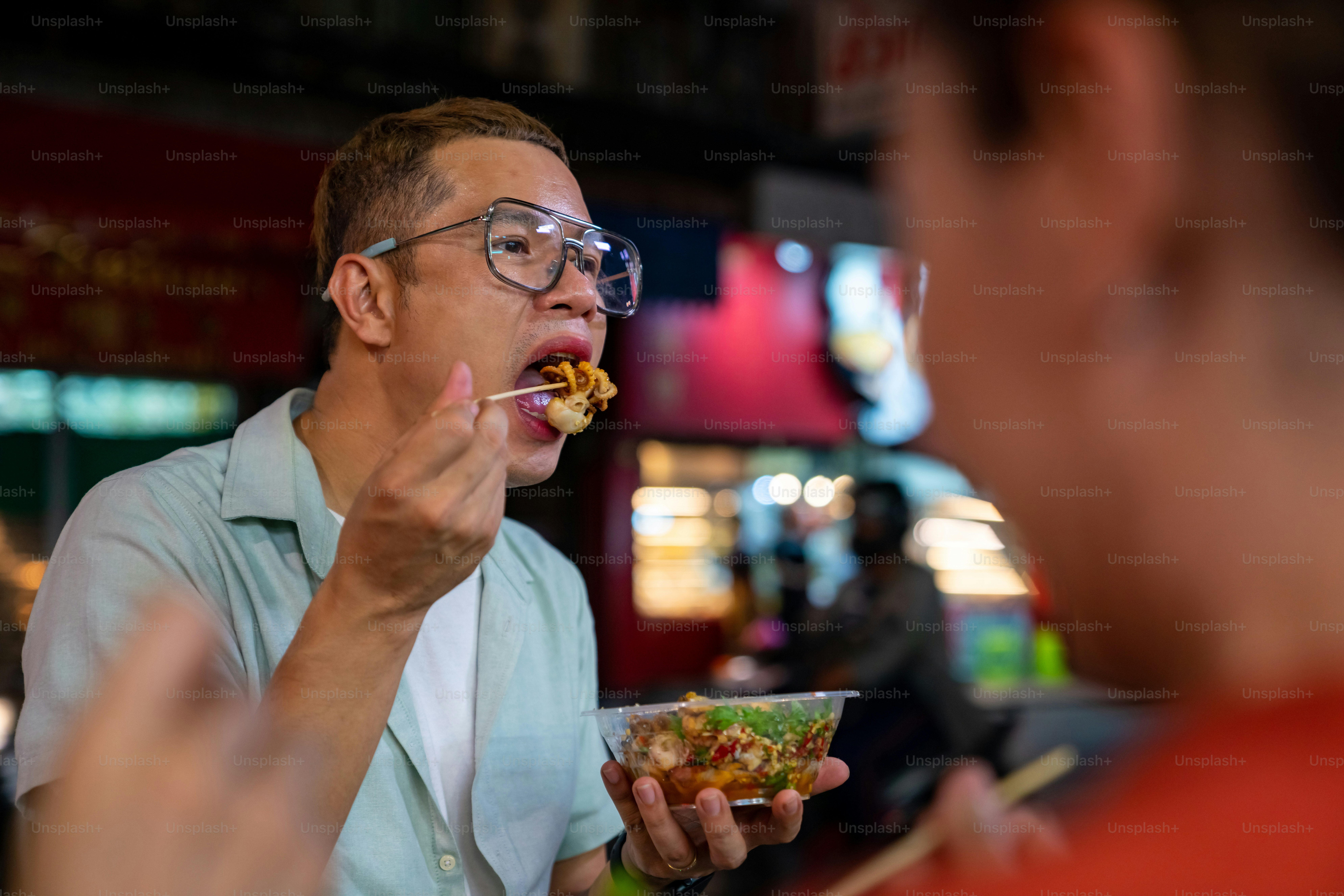 4K Gruppe asiatischer Frauen und LGBTQ-Leute Freunde Touristen genießen traditionelles Street Food BBQ Meeresfrüchte gegrillten Tintenfisch mit würziger Sauce zusammen auf China Town Street Night Market in Bangkok, Thailand