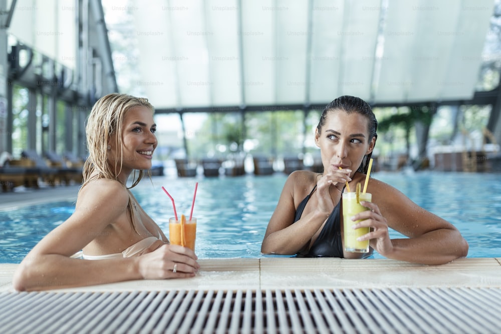Mulheres bonitas relaxando à beira da piscina de luxo. Fêmea na piscina do resort spa de viagem. Férias de luxo de verão. Retrato da mulher bonita na roupa de banho relaxando no spa da piscina.