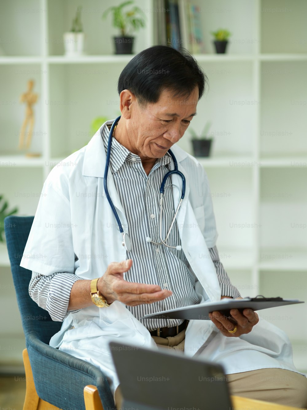 중년의 전문 남성 의사가 의료 클립 보드에서 부상당한 환자의 치료 계획을 확인하고 읽습니다.