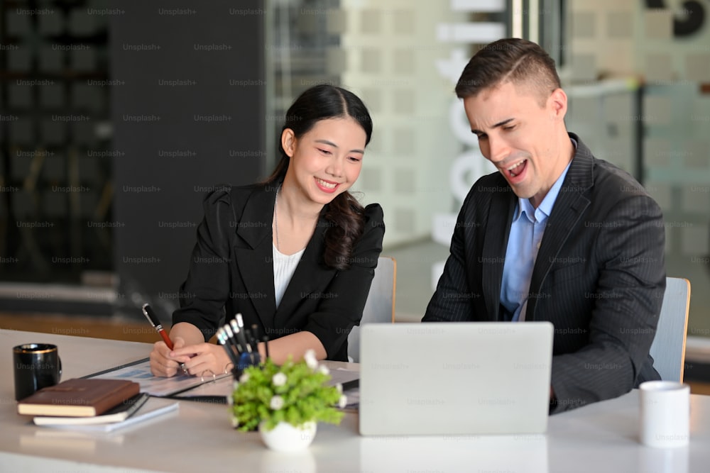 Dois dos empresários felizes e animados depois de olhar relatório de lucro de venda de negócios no computador portátil
