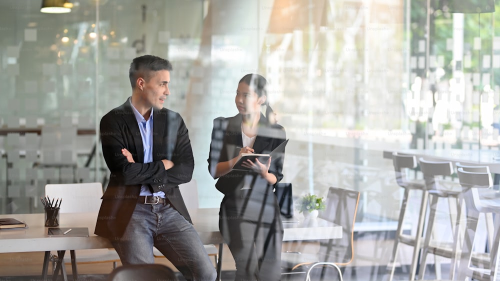 Successful businessman and businesswoman talking the business plan while standing in their workplace