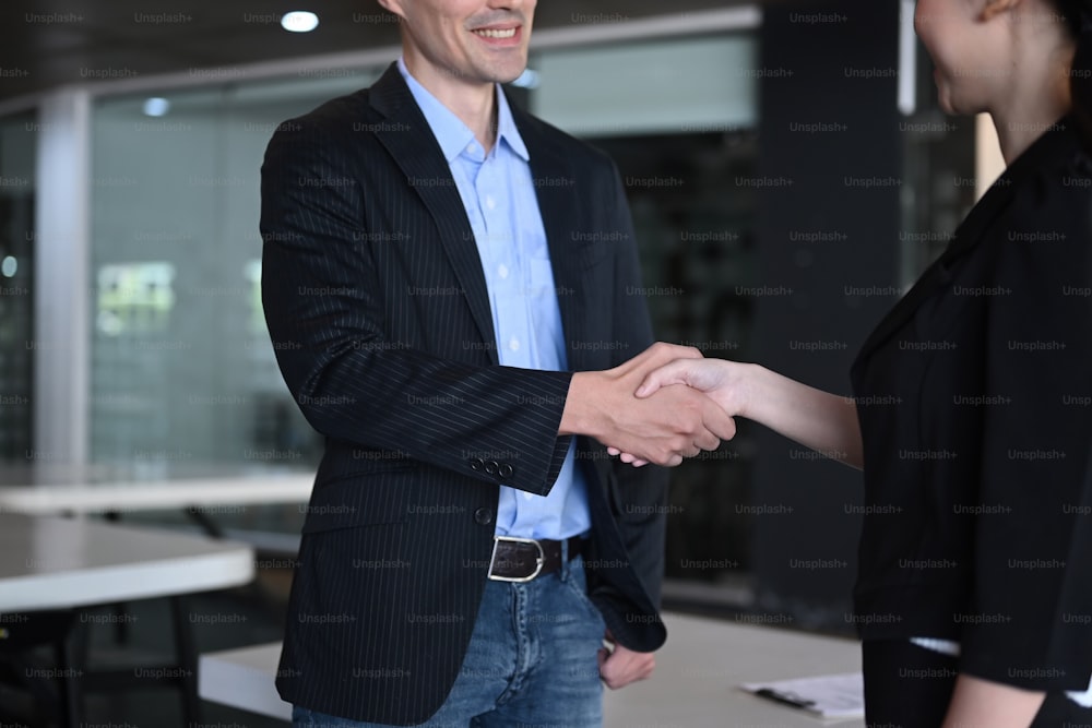 Deux partenaires d’affaires souriants se serrant la main après les négociations.