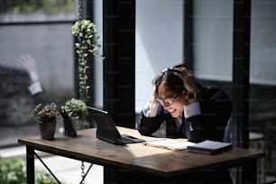 Frustrated businessman sitting at his working place in office and looking to computer laptop.