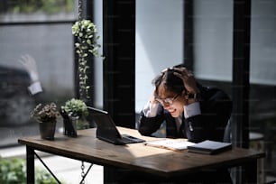Hombre de negocios frustrado sentado en su lugar de trabajo en la oficina y mirando a la computadora portátil.