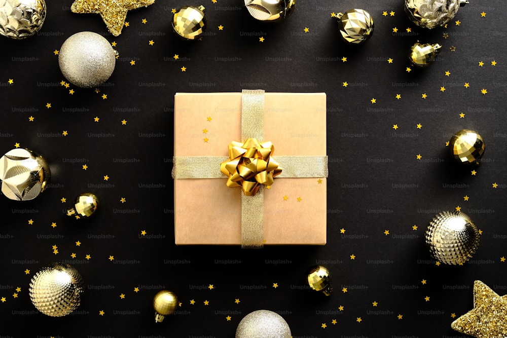어두운 검은 배경에 황금 공과 별 장식이 있는 크리스마스 선물. 플랫 레이, 평면도.