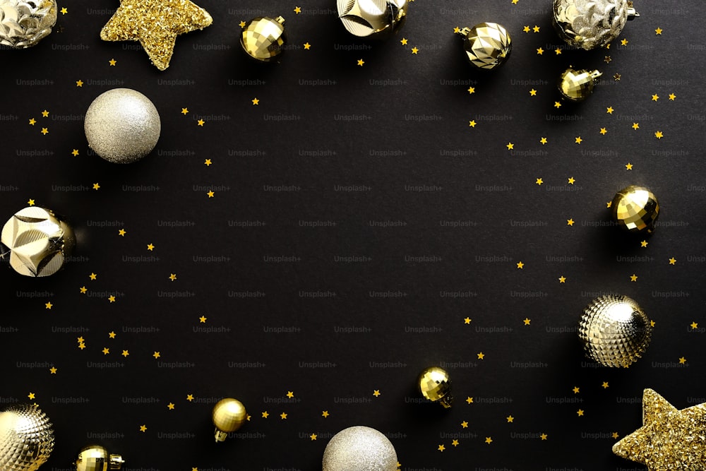 Composizione natalizia. Palline dorate piatte posate, decorazioni a stelle e coriandoli su sfondo nero scuro. Design del biglietto di auguri di Natale, modello di banner di Capodanno.