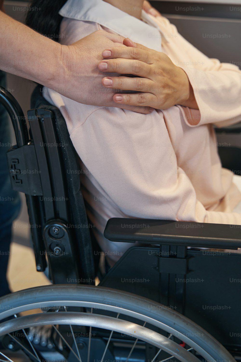 Cropped head top view of caring male embracing beloved wife who is using wheelchair indoors