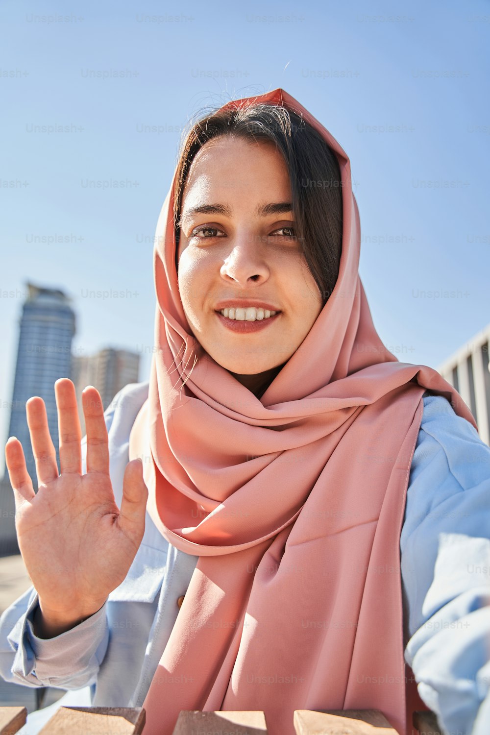 Hola. Vista de la bloguera islámica moderna saludando a sus suscriptores mientras graba su videoblog en la calle de verano