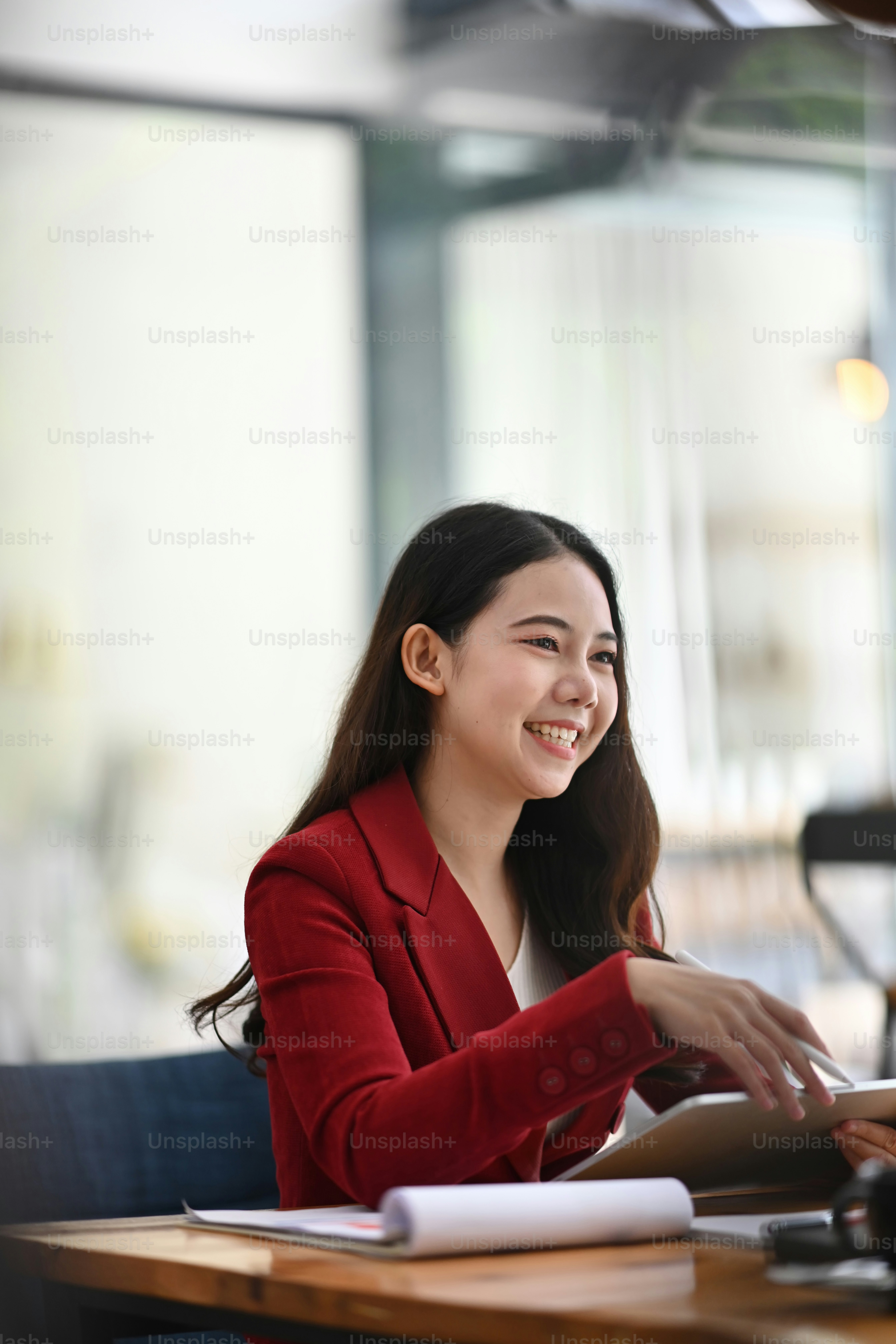 モダンなオフィスに座っている陽気なビジネスウーマン。