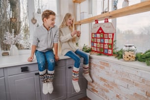 I bambini leggono i compiti dal calendario dell'avvento fatto a mano di Natale a forma di casa per il conto alla rovescia dei giorni fino al Natale sulla parete della stanza.