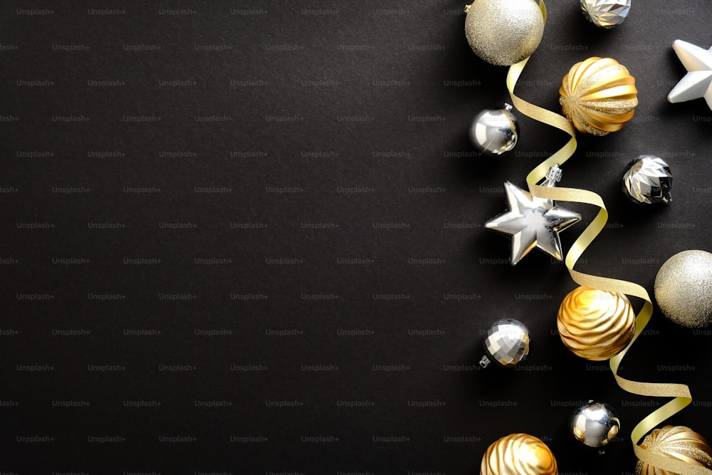 Composizione natalizia. Decorazioni di stelle e palle di Natale dorate e d'argento su sfondo nero scuro. Posa piatta, vista dall'alto, spazio di copia. Mockup del biglietto d'invito della festa di Natale, biglietto d'auguri di Capodanno