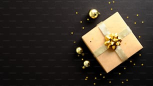 Frohe Weihnachten und ein glückliches neues Jahr Bannerdesign. Geschenkbox, goldene Kugelndekorationen, Konfetti auf dunkelschwarzem Hintergrund.