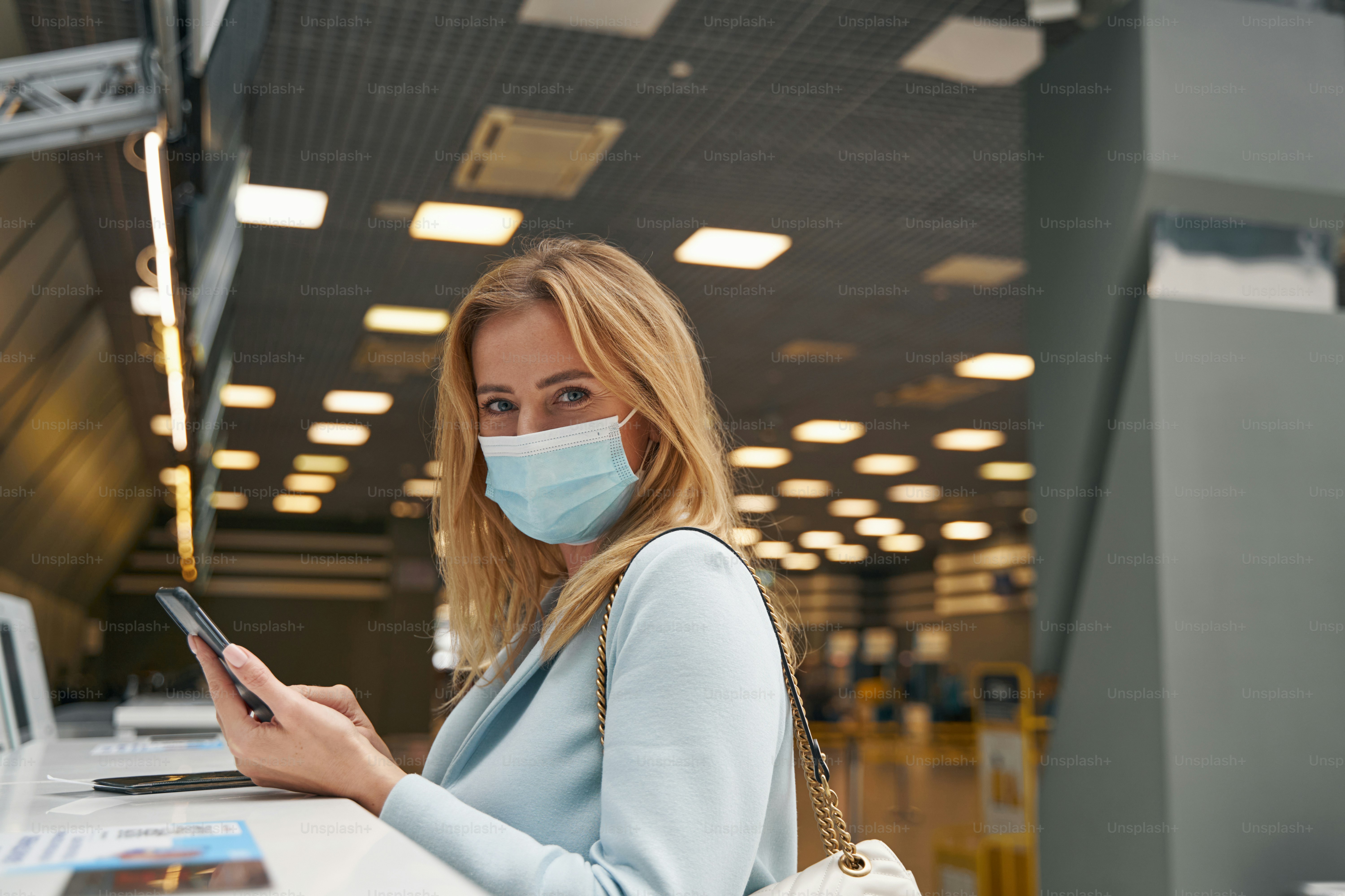 Portrait of air traveler with smartphone posing for camera at check-in counter