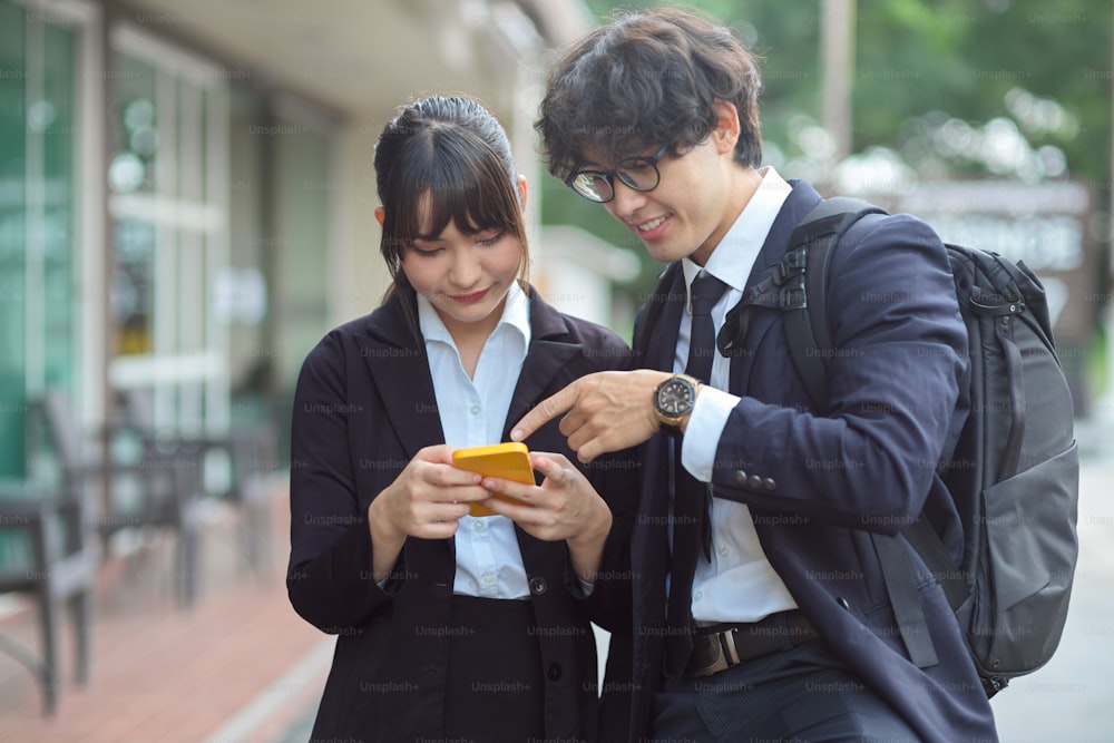 Millennial businessman and businesswoman on the street, using mobile phone application to find a locations.