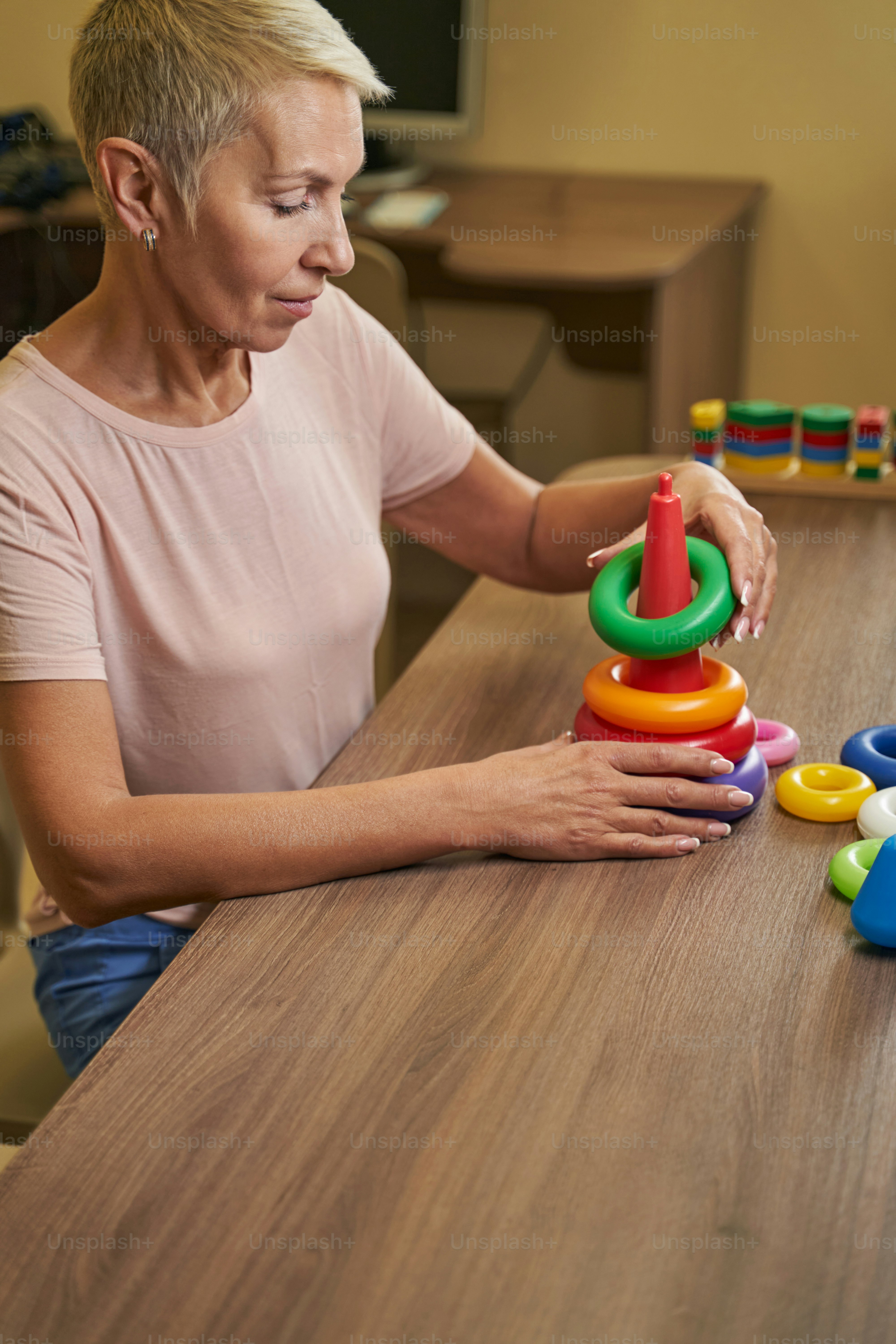 Photo of mature female patient during ergotherapy workshop with games to stimulate memory in neurological rehabilitation facility