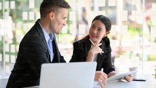 Two of attractive property investor sitting at modern office, discussing investment plans together.