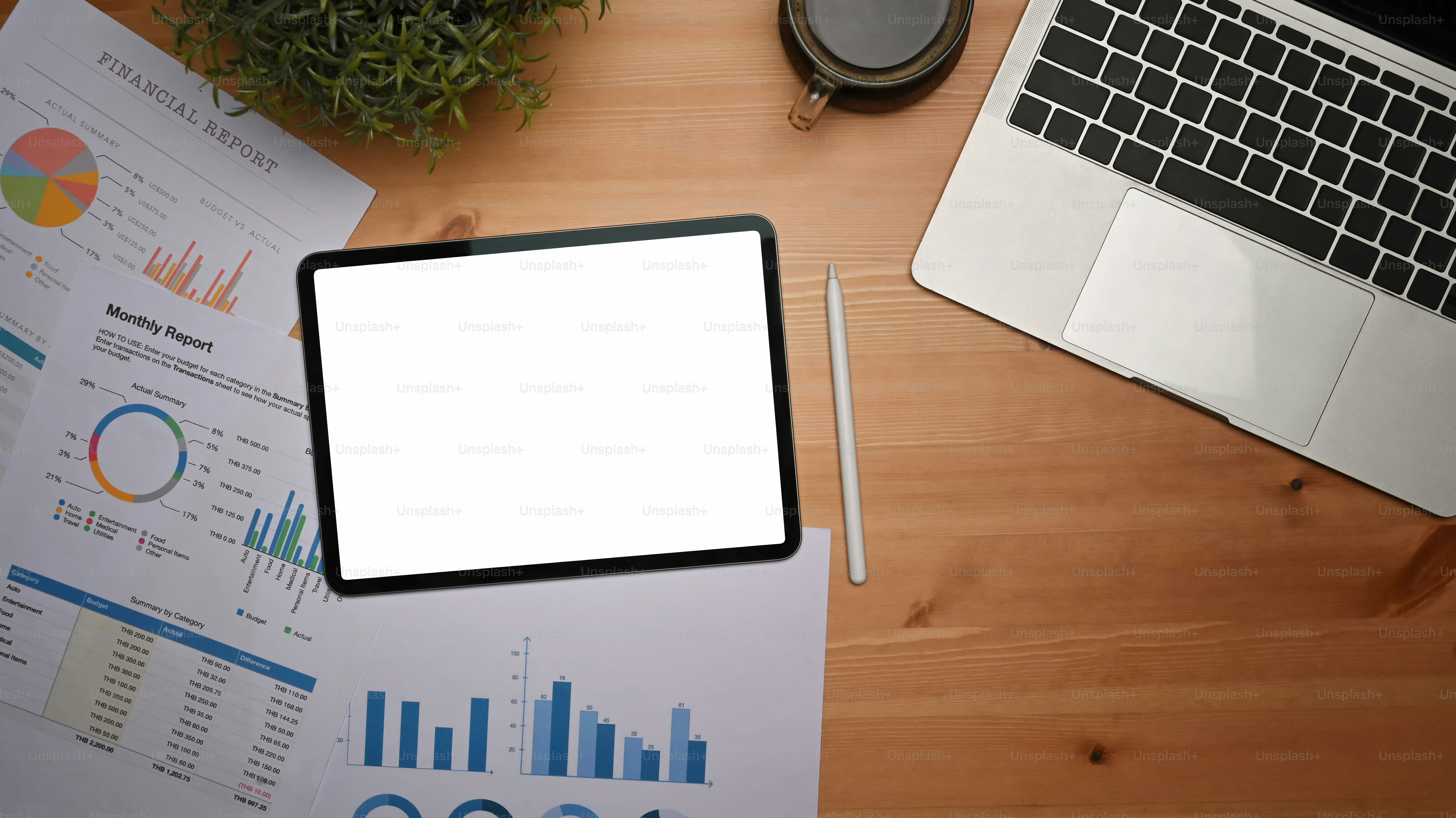 Mock up digital tablet, laptop computer and financial documents on wooden desk.