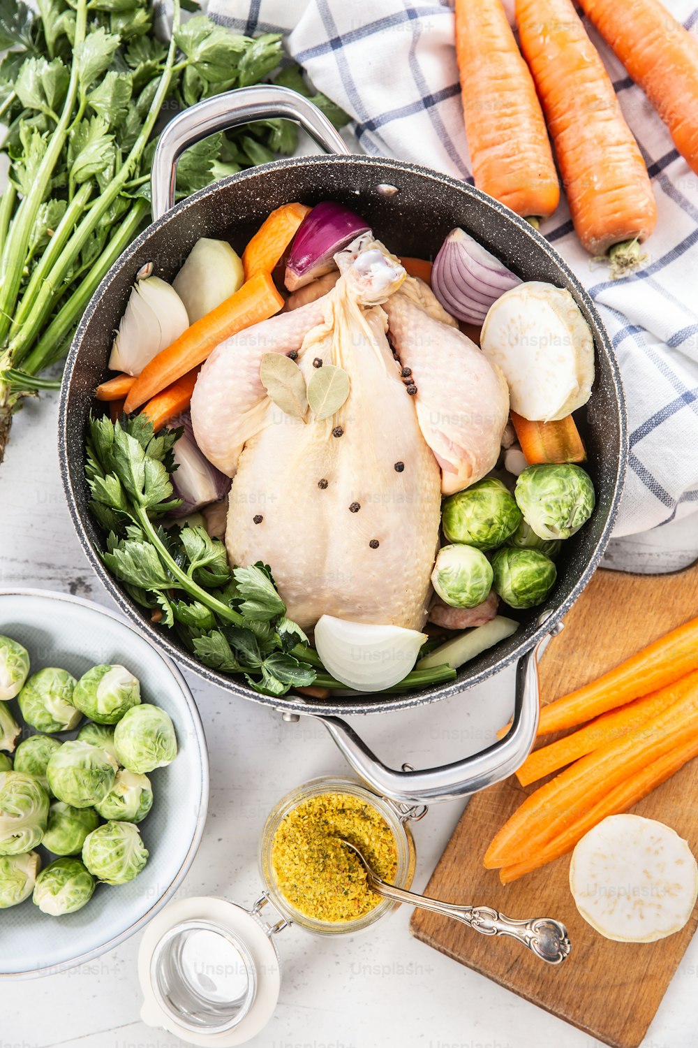 Chicken ready to cook broth with fresh root vegetables and spices - top of view.