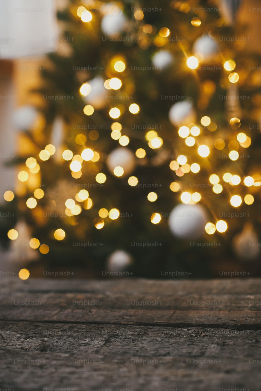 Christmas background. Rustic wood on background of christmas tree  lights golden bokeh. Space for text. Merry christmas and Happy Holidays!  Atmospheric christmas eve