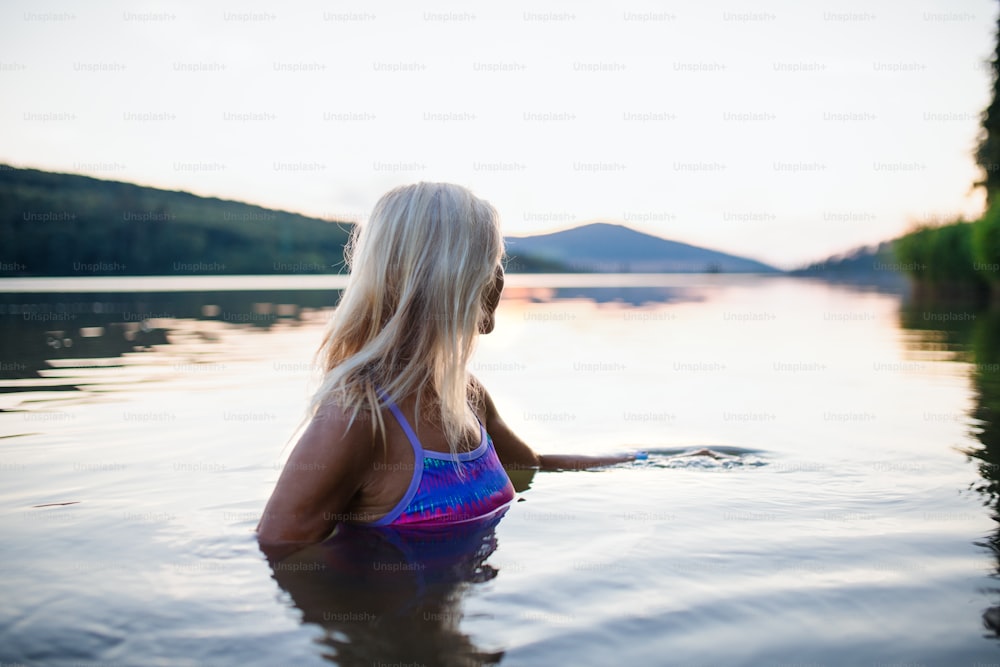 Una vista lateral de una nadadora mayor activa buceando al aire libre en el lago.