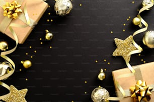 Elegant Christmas Flat lay composition. Golden decorations, balls, stars, gifts, confetti on black background. Christmas frame, banner design, Xmas greeting card mockup