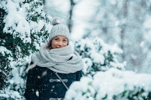 Beautiful young woman wearing scarf and a a hat on a cold winter day during snow