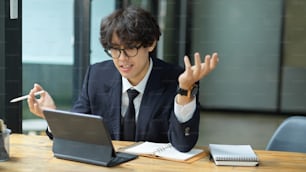 An executive businessman conducts an online consultation with board members using a tablet computer.