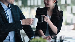 Erfolgreiche Geschäftsleute stoßen Tassen Kaffee an, um nach erfolgreicher Erledigung wichtiger Arbeit gemeinsam zu feiern.