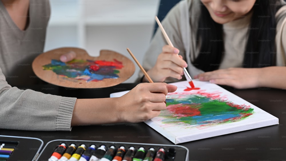 Smiling asian girl having fun painting with her mother at home.