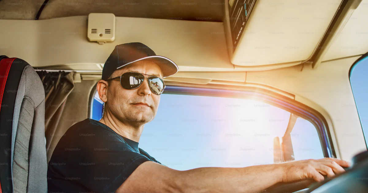 Gutaussehender erfahrener LKW-Fahrer mit Hut, der sitzt und seinen LKW ...