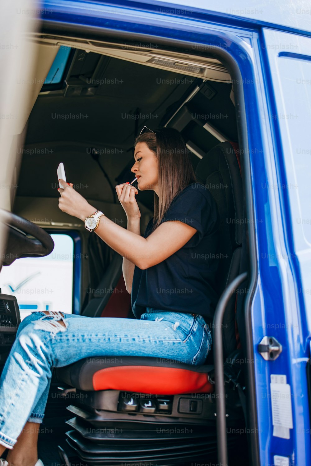 Portrait of beautiful young woman professional truck driver sitting and resting after long drive. Inside of vehicle. People and transportation concept.