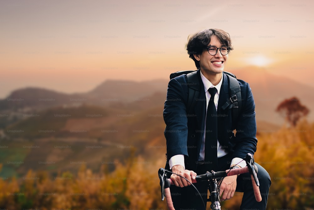아름다운 산 풍경 배경을 가진 도로에 자전거를 타고 서 있는 웃는 사업가.