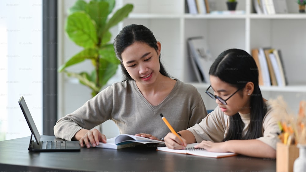 Young mother helping her daughter with homework at home.