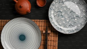 Dressage de table avec de belles assiettes en céramique en porcelaine et un service à thé asiatique sur une table à manger. Vue de dessus