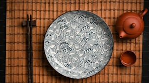 箸とお茶が竹のランチョンマットにセットされたアジアの磁器の陶板。�上面図、フラットレイ