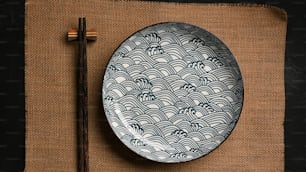 아시아 그릇 개념, 갈색 플레이스 매트에 젓가락이 있는 세라믹 접시. 도자기, 파란색과 흰색 접시. 상위 뷰
