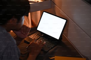 Cropped shot young man working with computer tablet at late night.