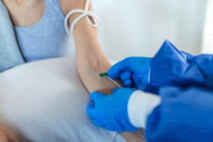 Senior woman sitting in the hospital chair while receiving IV infusion in medicine center