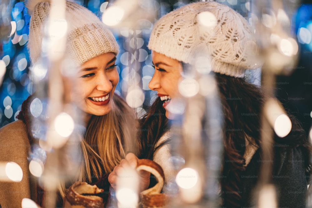 Happy young women friends having fun, enjoying moments together in christmas decorated background.