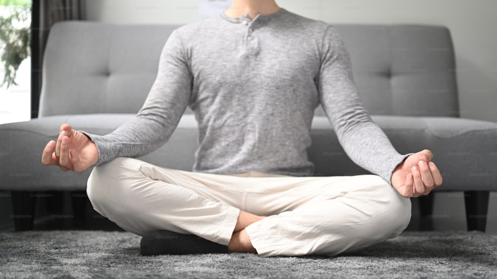 Friedlicher Mann, der Yoga in Lotuspose zu Hause praktiziert.