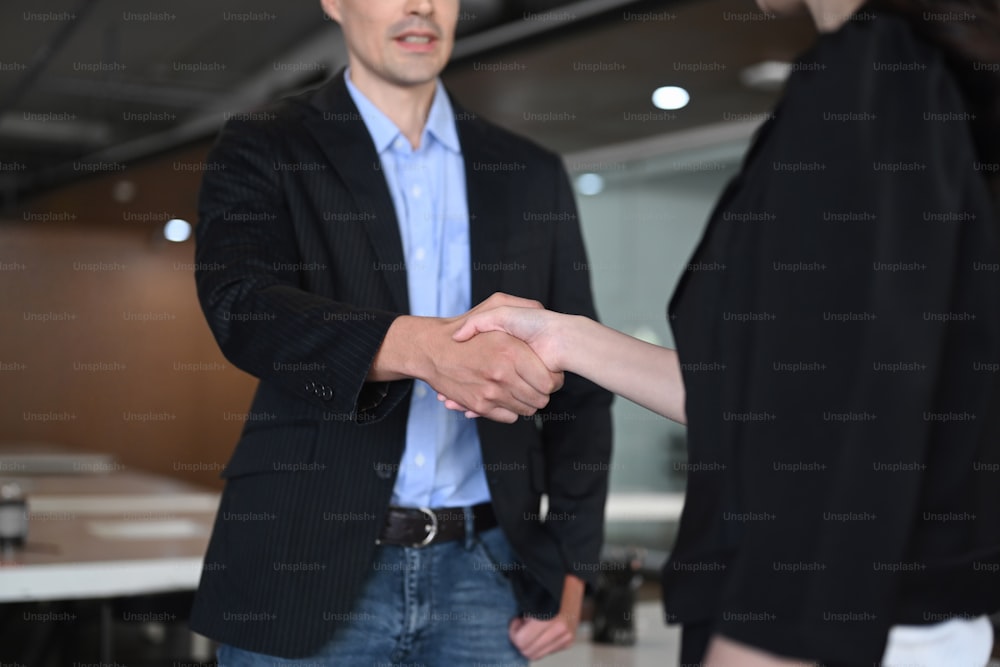 Businesspeople shaking hands after finishing up meeting or negotiation in office.