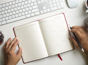 Vista superior, páginas en blanco en el libro del diario en la mesa de trabajo moderna. las manos de un hombre con un libro. Concepto de estudio