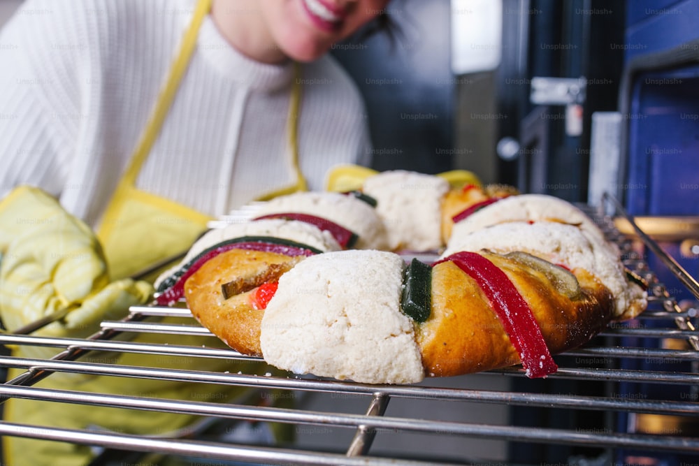 mexican woman baking a traditional rosca de reyes or epiphany cake on the oven in kitchen at home for Kings Day in Mexico Latin America